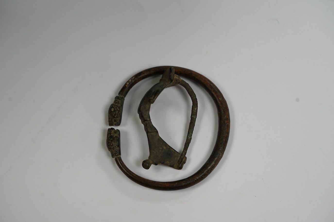 A bronze bracelet, probably Luristan and a Roman bronze fibula brooch (2). Condition - fair